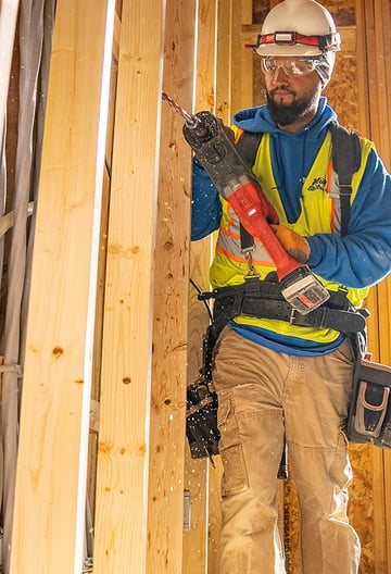 Worker drilling into wood stud